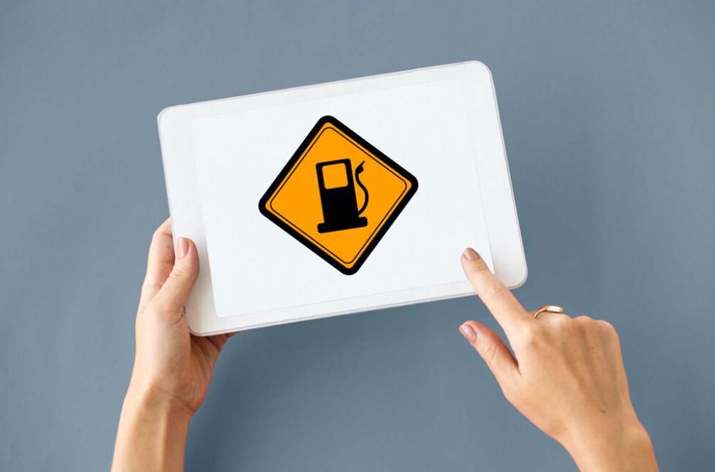 Hand pointing at gasoline warning sign on a tablet.